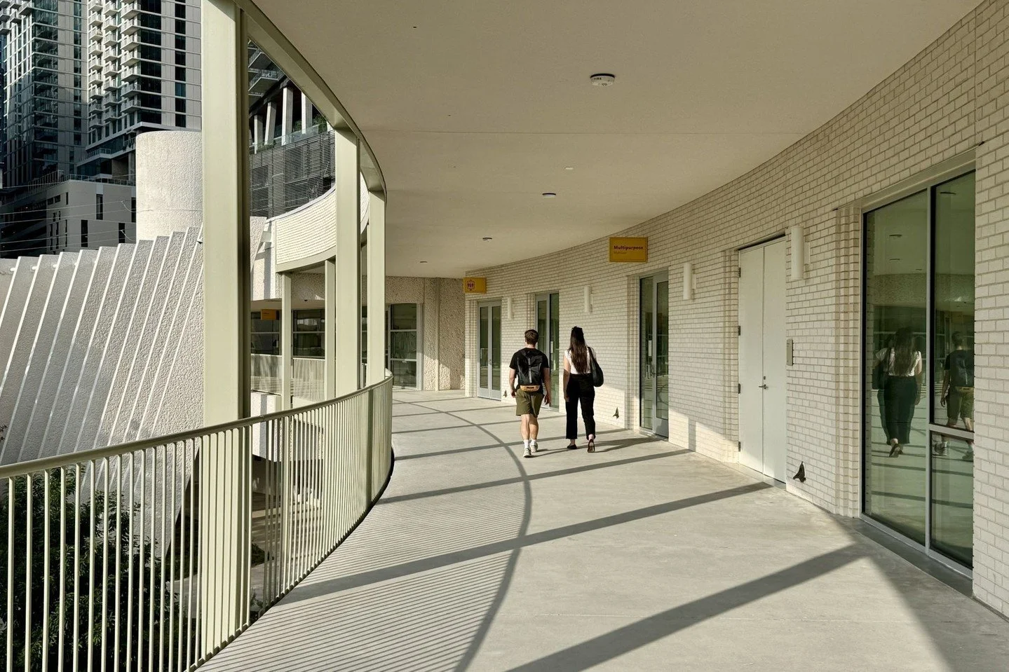 The exterior walkways are supported by thin, paired columns whose visual lightness contrasts the heavy precast fins of the original structure while extending the existing circulation. New bilingual signage throughout the facility improves wayfinding 