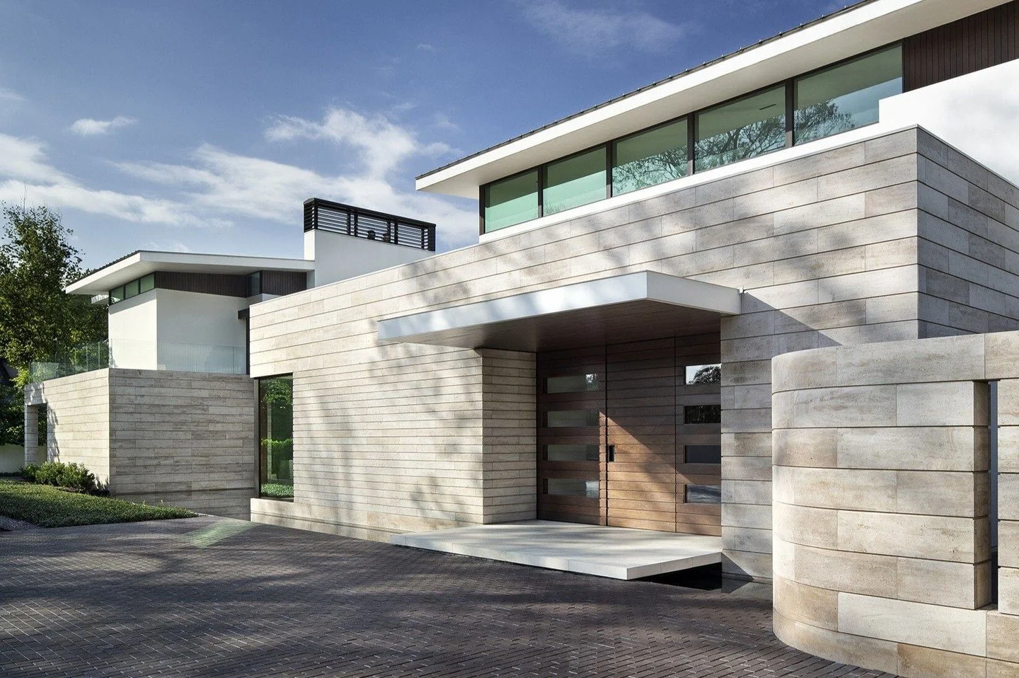 The lower level of the #WestResidence is clad in horizontal bands of Crema Albi limestone. This limestone base continues around the house from the front to the back, complemented by white stucco on the upper floor and offset by dark mahogany at the e
