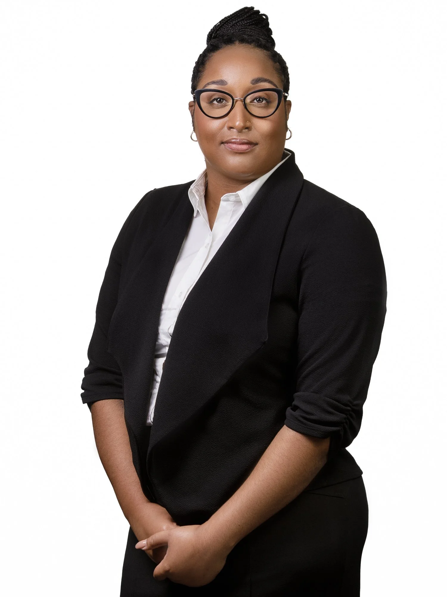 Person wearing glasses and a black blazer, standing against a white background.
