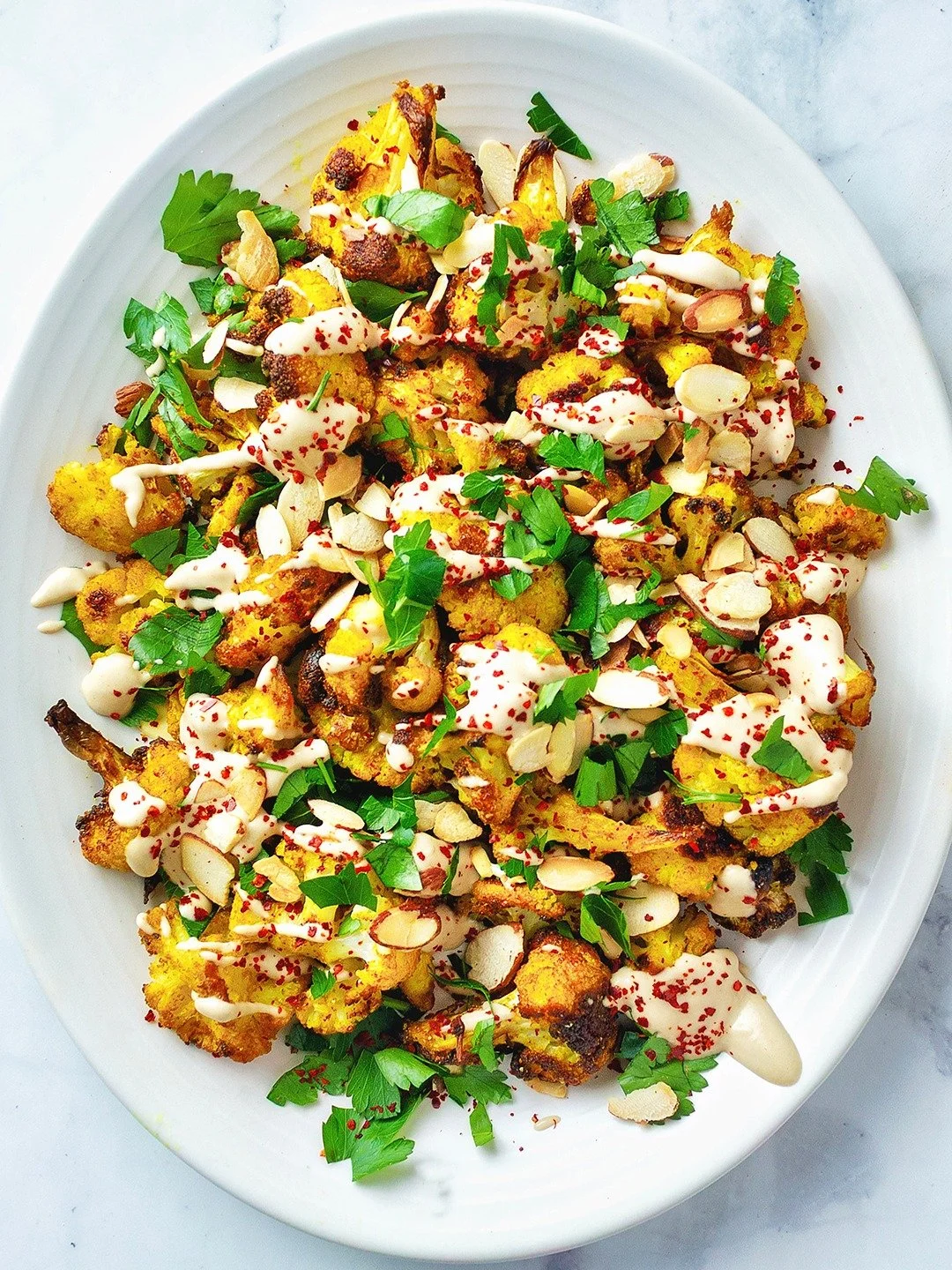 Spiced roasted cauliflower with tahini, almonds, parsley and Aleppo pepper.

I make this a side dish but I'm also very happy to eat it by itself. It works warm or at room temp. 

It's not complicated: cauliflower florets tossed with cumin, coriander,