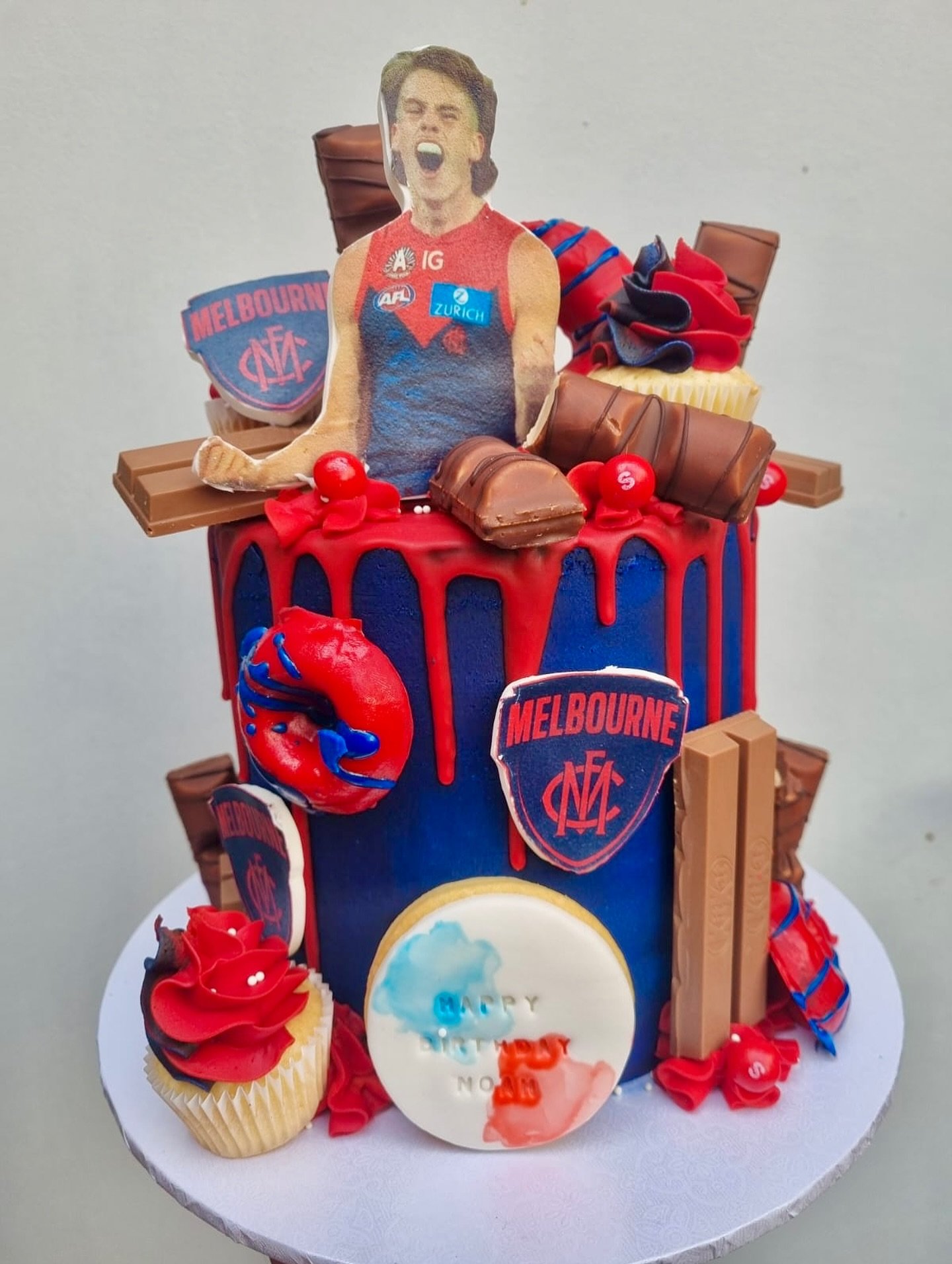 🎂🏉 Melbourne Demon Cake 🏉🎂
Celebrating footy fever in the sweetest way possible!
This custom cake for Noah features bold red &amp; blue drip, edible team logos, a roaring topper of his fave player, and all his fave treats &bull; KitKats, Kinder b
