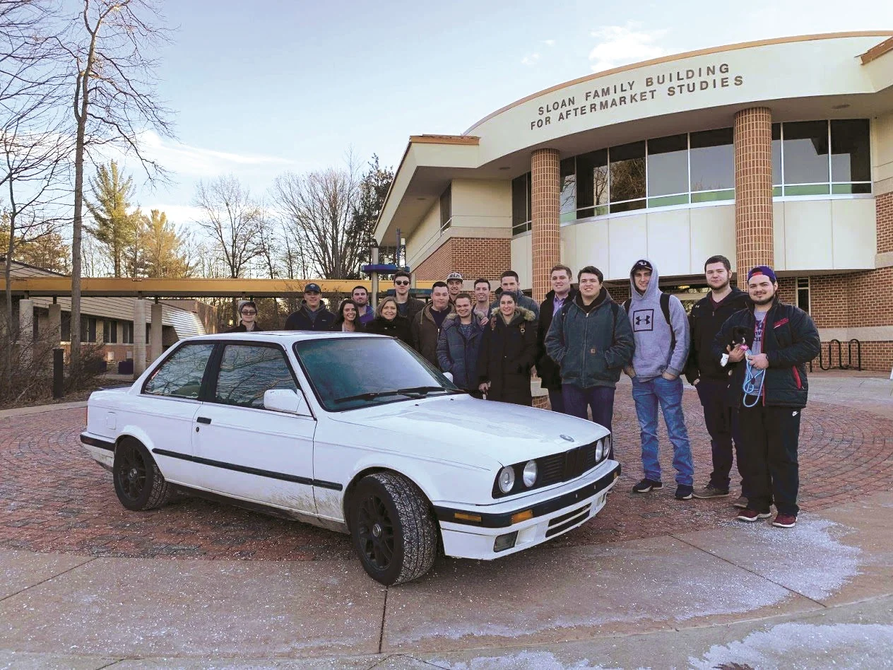 Members of the fall 2018 Project 100 winner, the Aftermarket Club, gathered around the 1989 BMW E30 they bought.