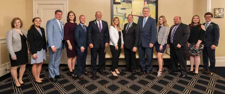 Outstanding Alumni Award recipients stand with their student presenter. Full names andgraduation years are listed below. From left to right: Grafilo, Ford, Sutherlin, Pung-Gottschalk, A. Smith, C. Smith, Sian, Wildstein, President Pretty, Lindow, Boursaw, McLavy and Fletcher.