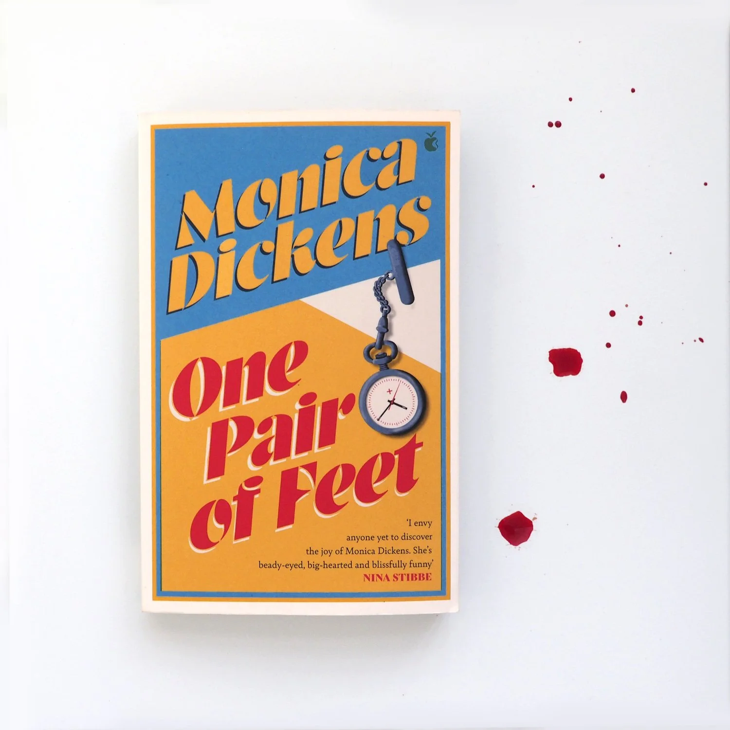 A paperback book on a blood-spattered background. The book is One Pair of Feet by Monica Dickens.