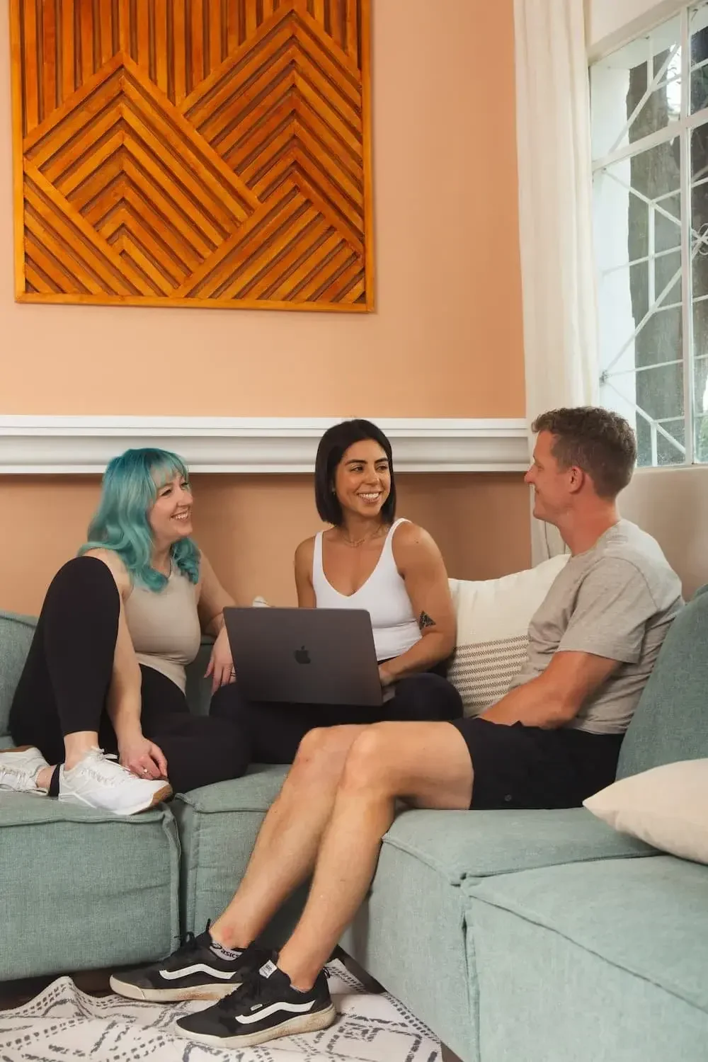 Coach Whitney, Coach Kate and Coach Kenny sitting on a sofa looking at each other
