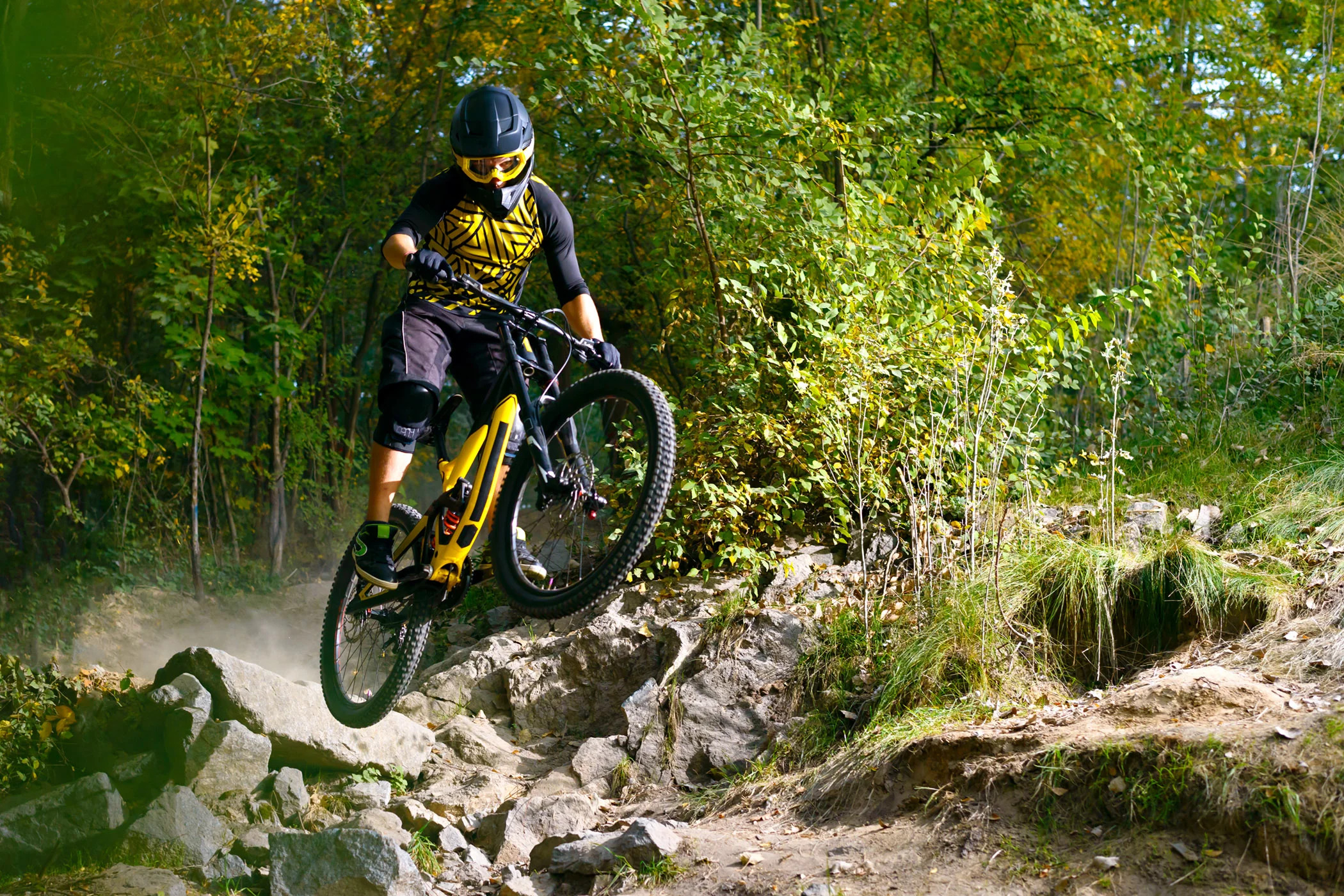 Mountain biker catching air on a rocky downhill bike trail.