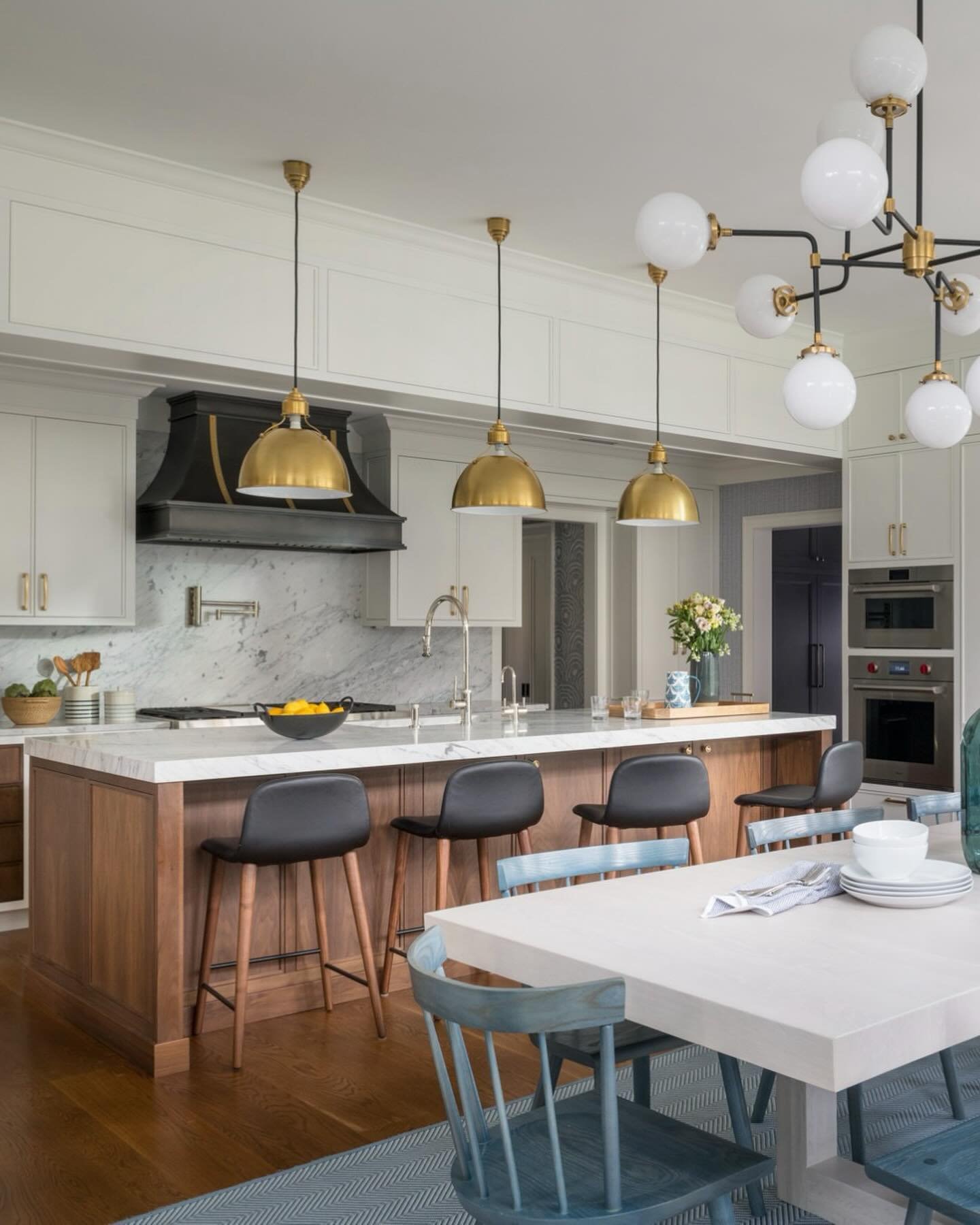 Keeping it classic, clean and sophisticated, this kitchen expansion is packed with design details. Seamless Carrara Marble slabs on both the backsplash and center island, custom range hood, walnut center island, two-tone cabinetry flanking the range 