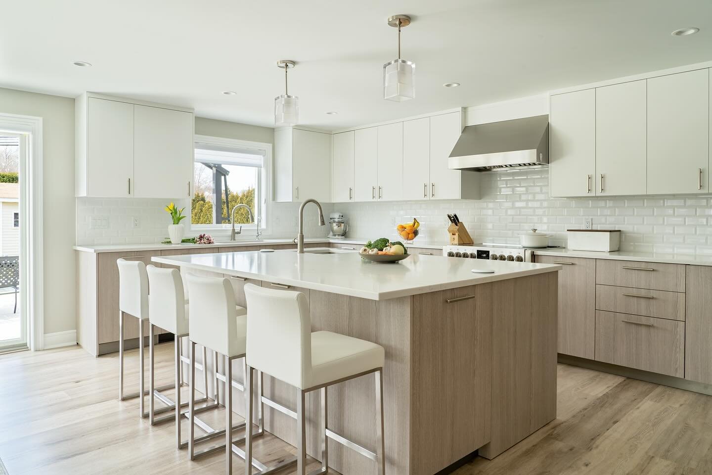 This kitchen has all the ingredients to host the perfect get-together. It has plenty of space, a neutral color palette with natural materials, gorgeous garden views, and a layout ideal for socializing while the chef of the family prepares delicious d