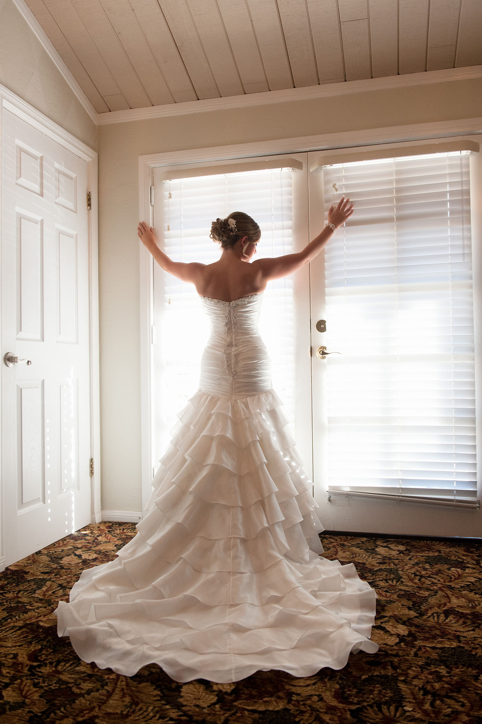 Bride facing window, displaying her wedding dress train at Grand Tradition Estate & Gardens in Fallbrook.
