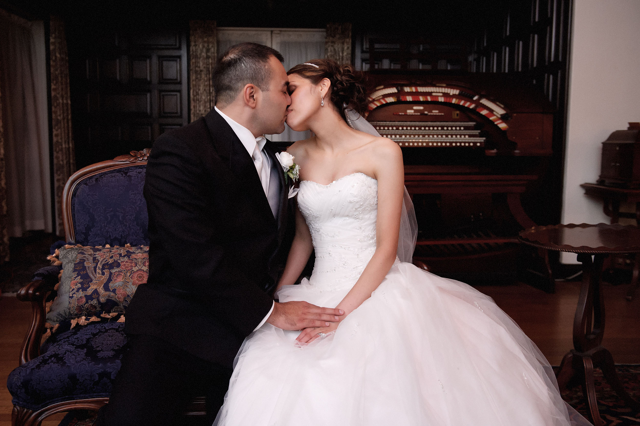 Bride and groom kissing in front of antique piano at the Kellogg House at Cal Poly Pomona.