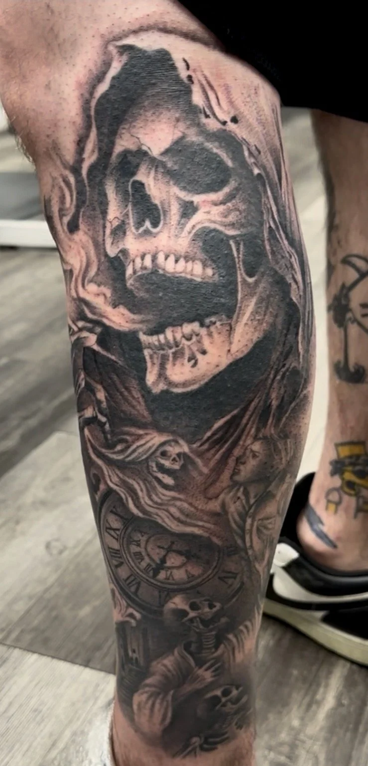 Black and gray tattoo of a grinning skull with smoke or flames around it, clock with Roman numerals, and skeleton figures.