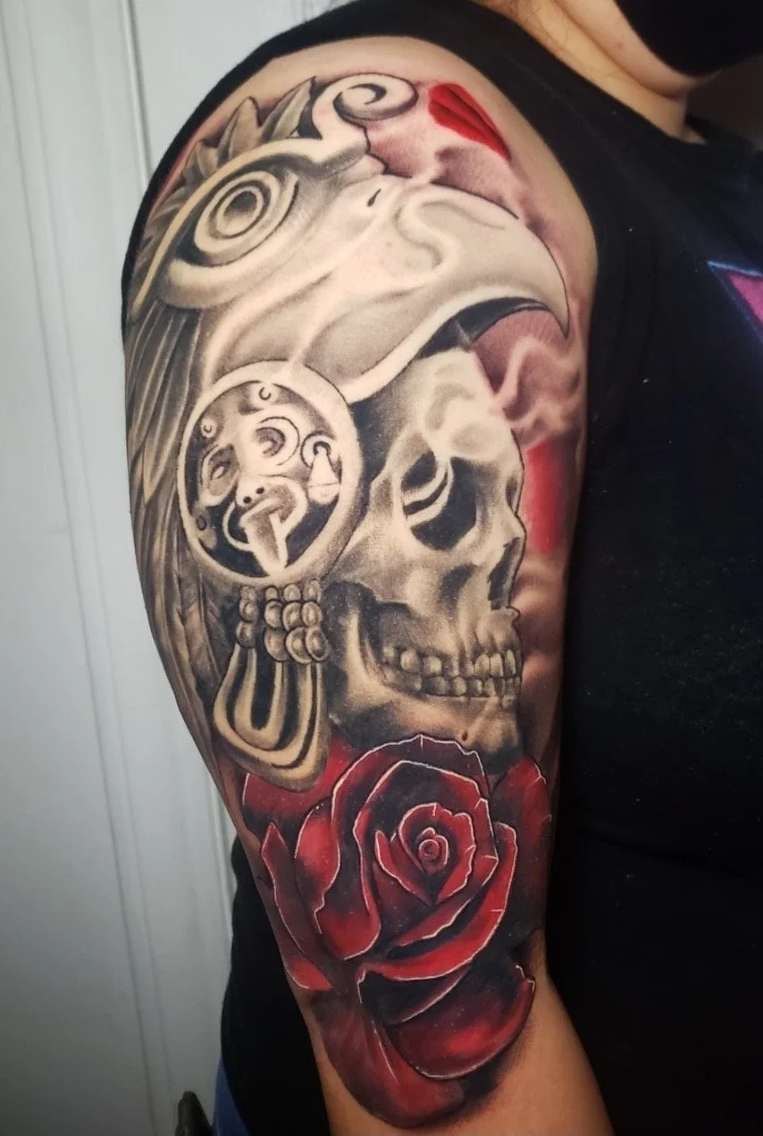 Tattoo of a skull, a Native American chief in profile, and a red rose on a person's arm.