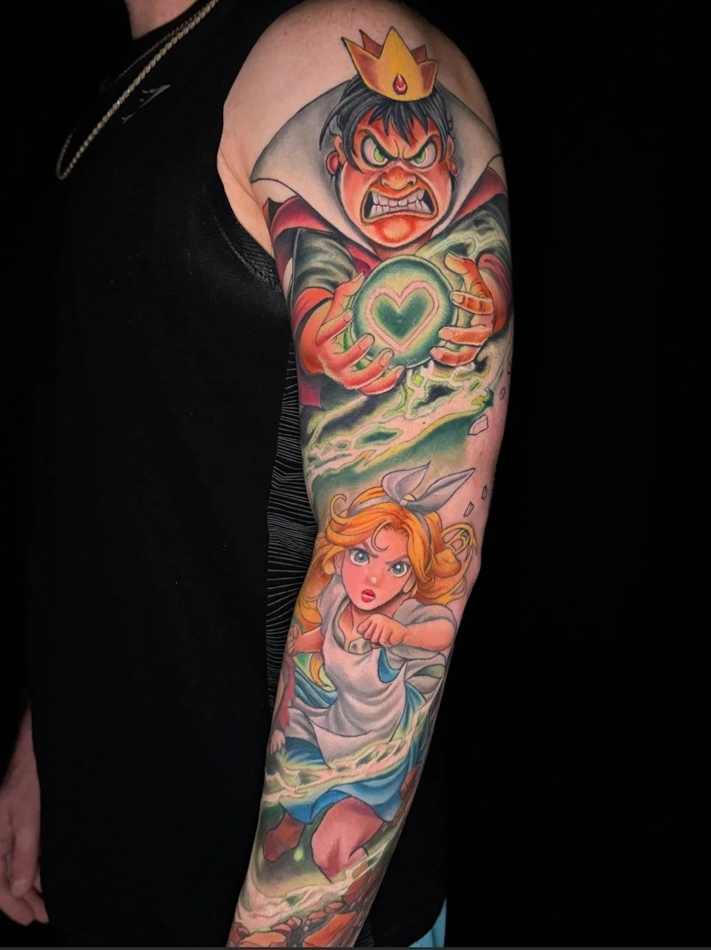 Colorful tattoo on person's arm featuring a fierce cartoon prince with a crown holding a glowing heart-shaped object, and a determined princess with flowing hair and a dress running forward.