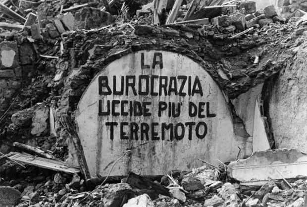  Slogan dipinto su un muro distrutto di Salaparuta, “La burocrazia uccide più del terremoto”, 1968   