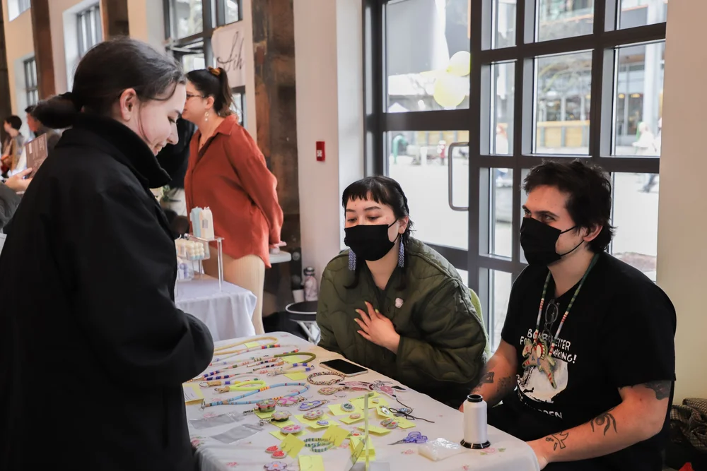 A shopper talking with local makers at a market booth