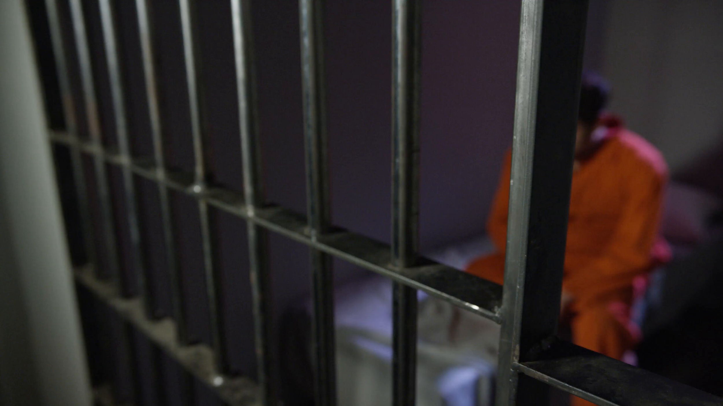 man-sitting-on-the-edge-of-his-bed-in-jail-cell-behind-bars_samt1izsz__F0000.png