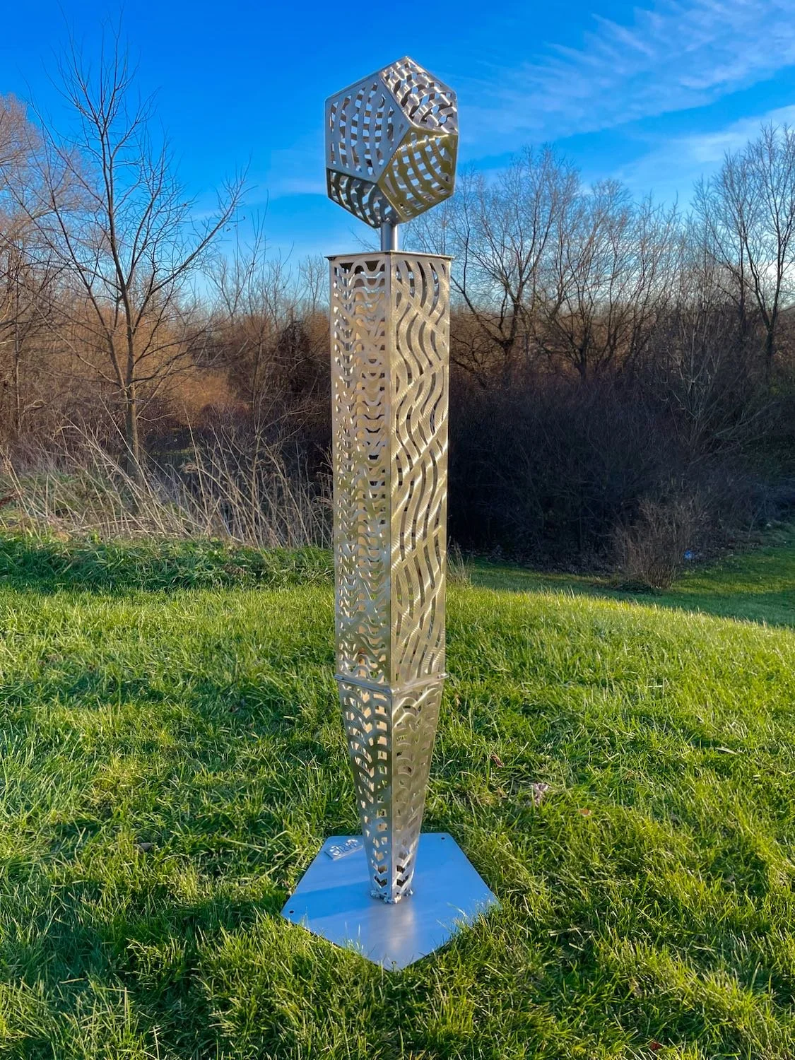 A stainless steel sculpture featuring cut out portions symbolizing fire, earth, air, water, and energy