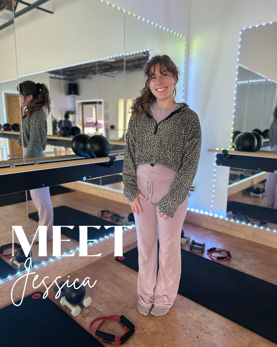 A woman in workout clothes smiling in a fitness studio with mirrors, workout equipment, and colorful LED lights.