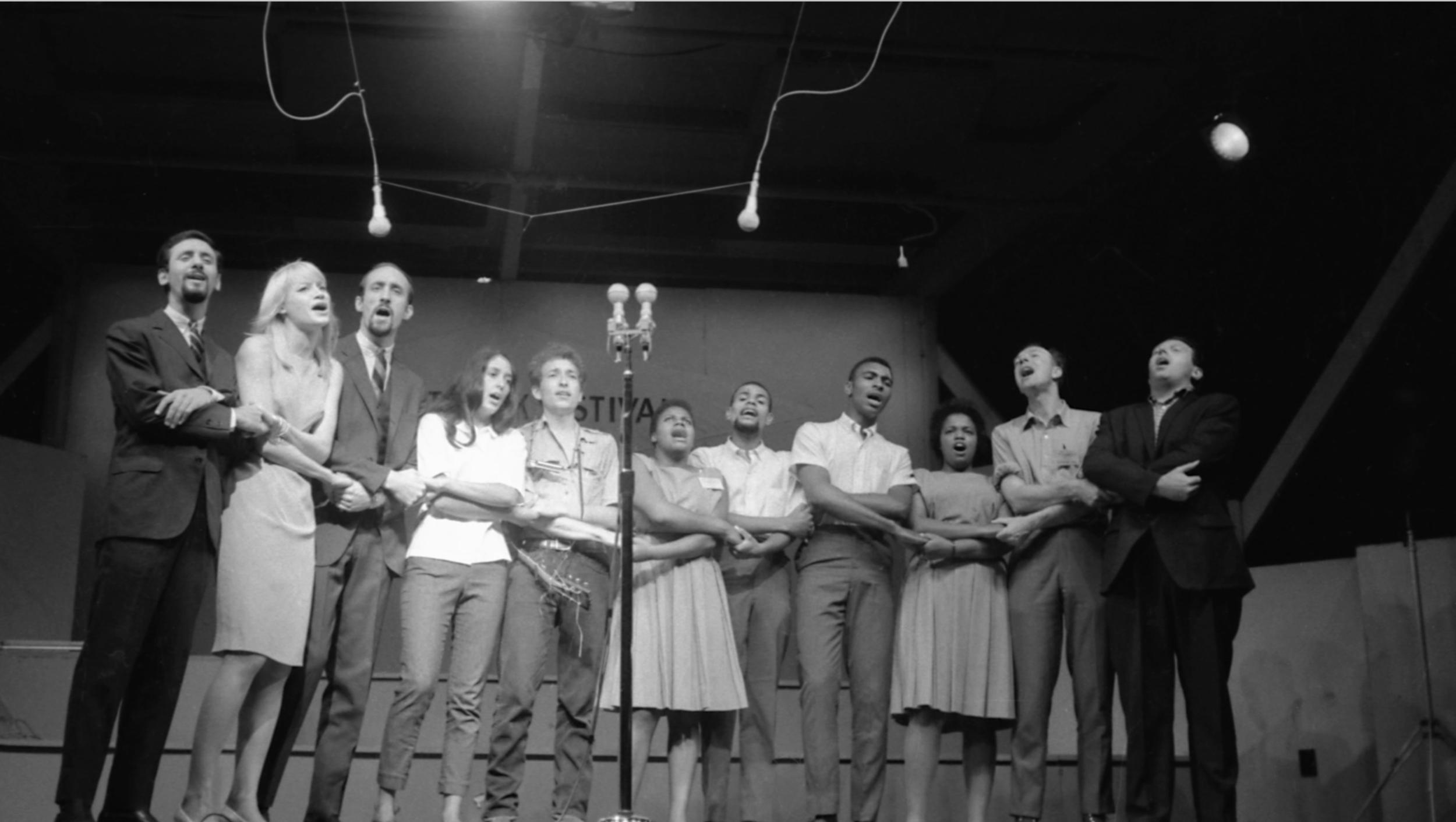  Peter Yarrow, Mary Travers, Paul Stookey, Joan Baez, Bob Dylan, Bernice Reagon, Cordell Reagon, Charles Neblett, Rutha Harris, Pete Seeger, and Theodore Bikel singing “We Shall Overcome” at Newport Folk Festival (July 1963). Photo credit: Rowland Sc