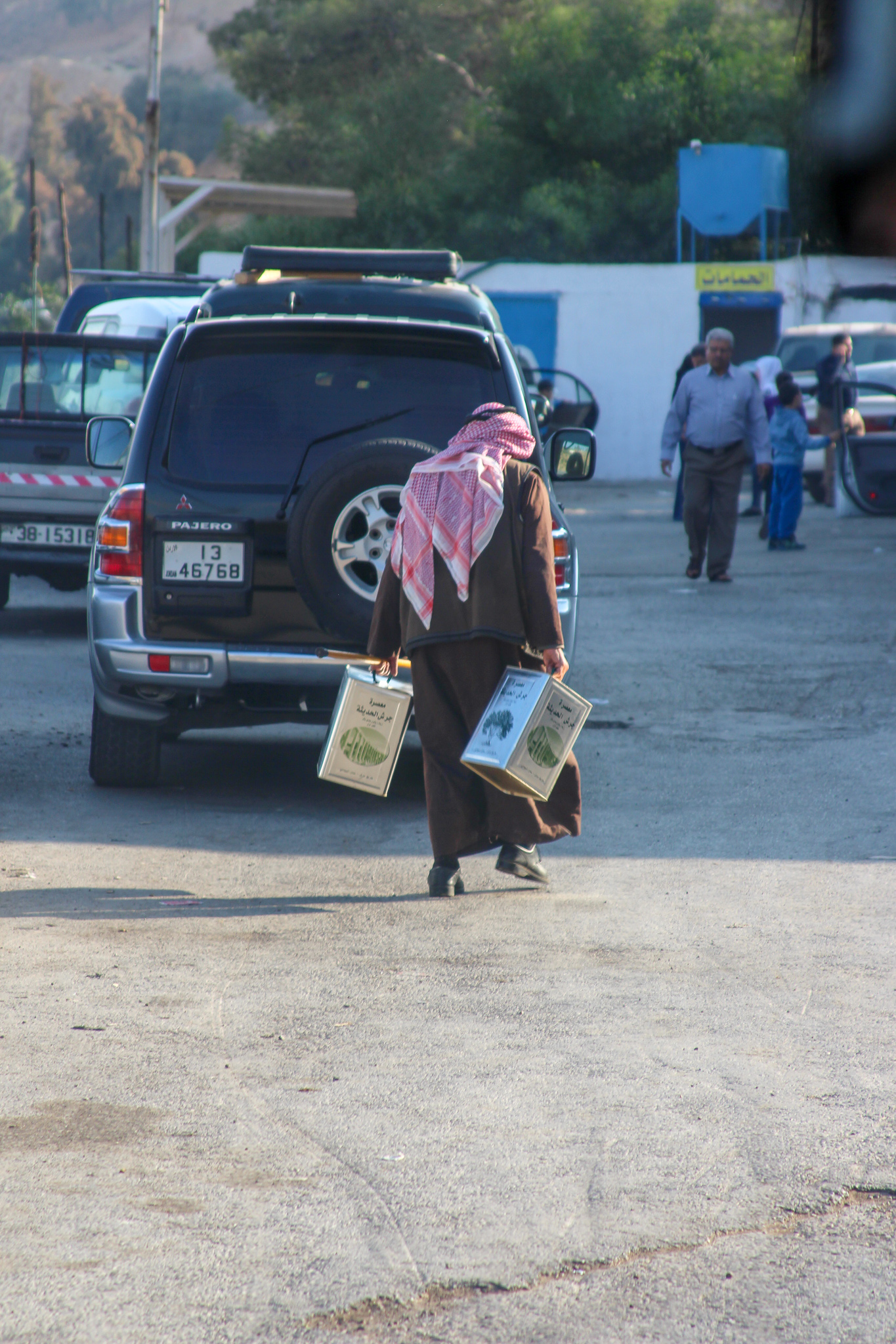 A man carrying two large containers of olive oil fresh from the presses.