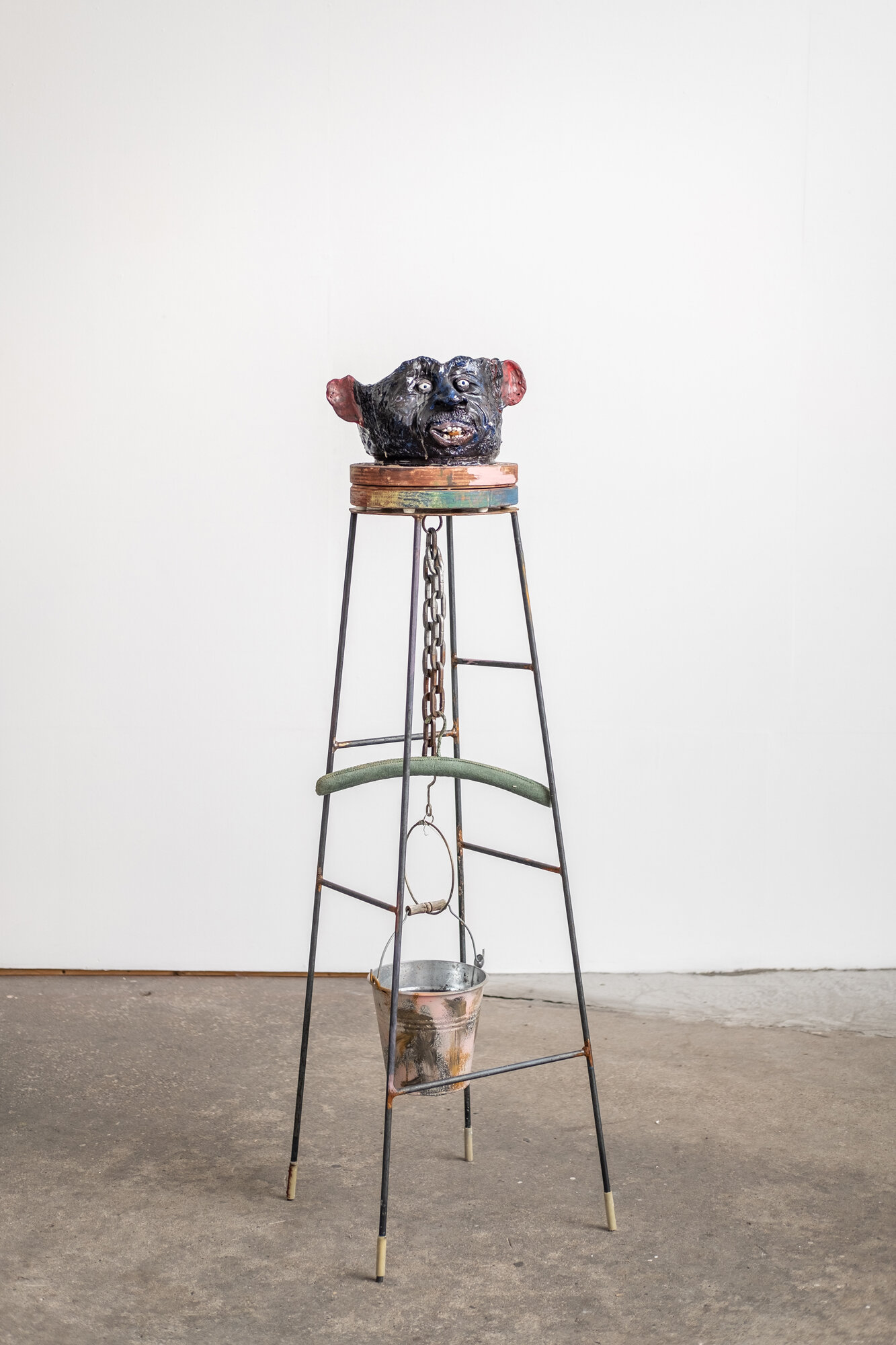   Q is for cumber’, 2021,  Ceramics, wax, resin, wood, metal, clothing hanger, spray paint and cigarette buds, oil paint, plastic and wood stain 162 x 50 x 46cm    Part of the exhibition That Clinking Clanking Clunking.  A humanoid chair sculpture fu