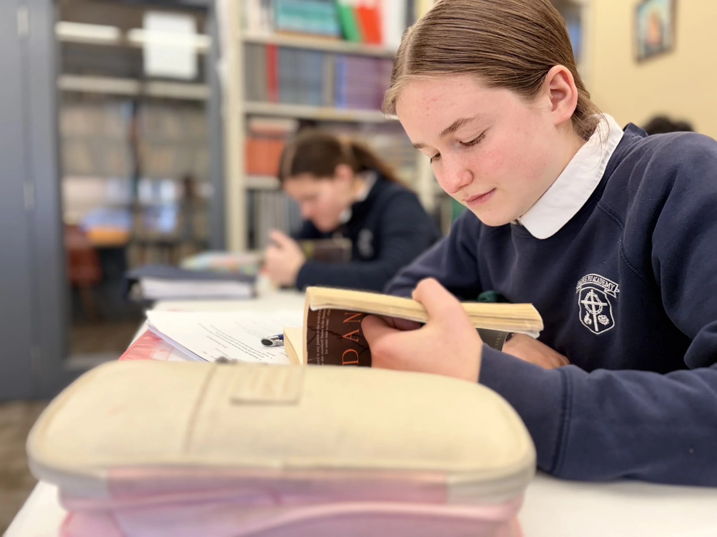 A female high school student reading from a book and studying before class