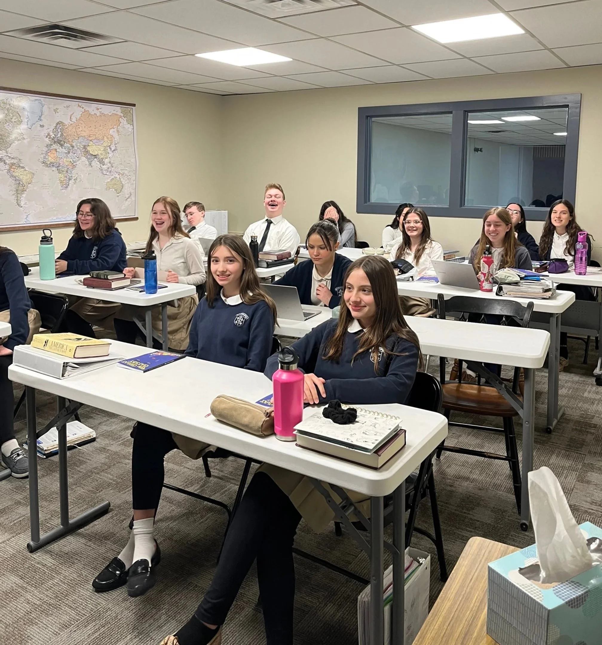 Classroom full of middle school students sitting at desks, smiling and laughing during class.