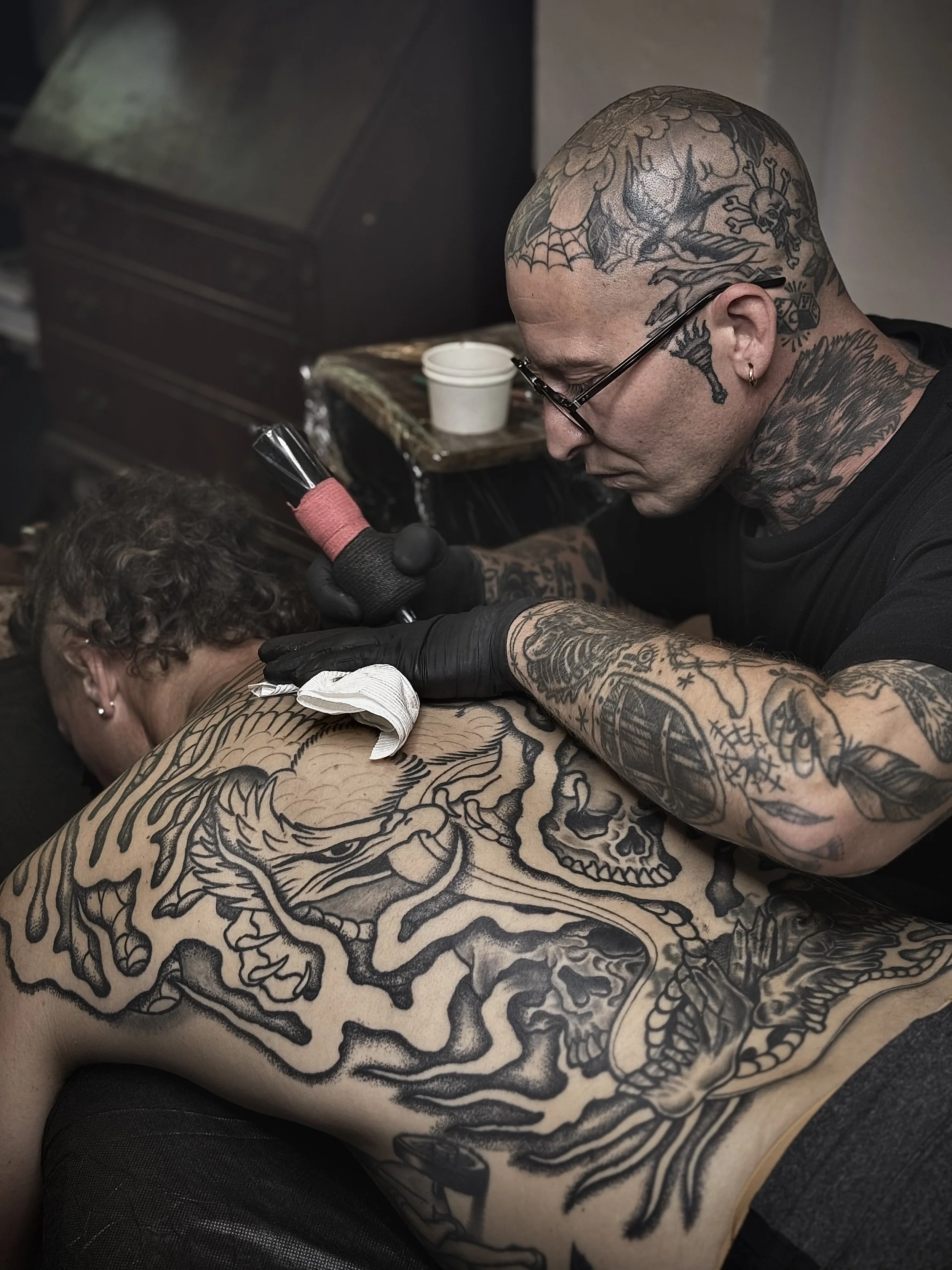 tattoo artist tattooing back piece bold traditional snake eagle 