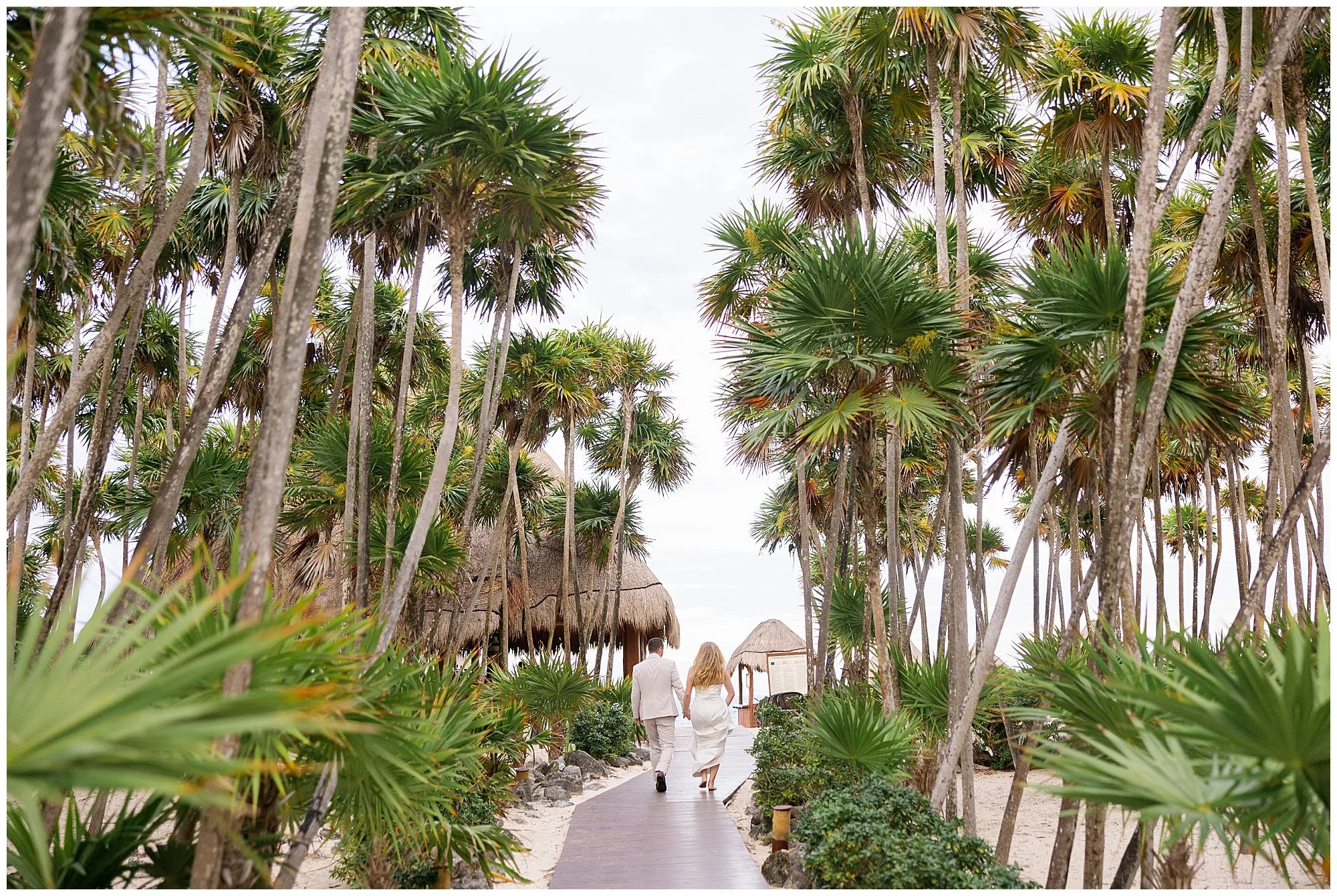  bride and groom walking down palm tree pathway at valentin imperial resort in riviera maya 