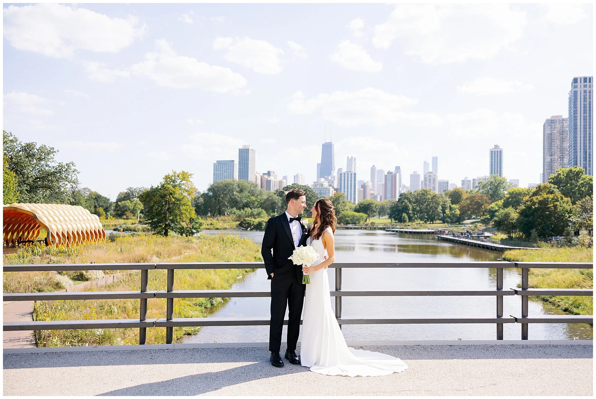 bride and groom in front of chicago skyline looking at each other at lincoln park south pond 