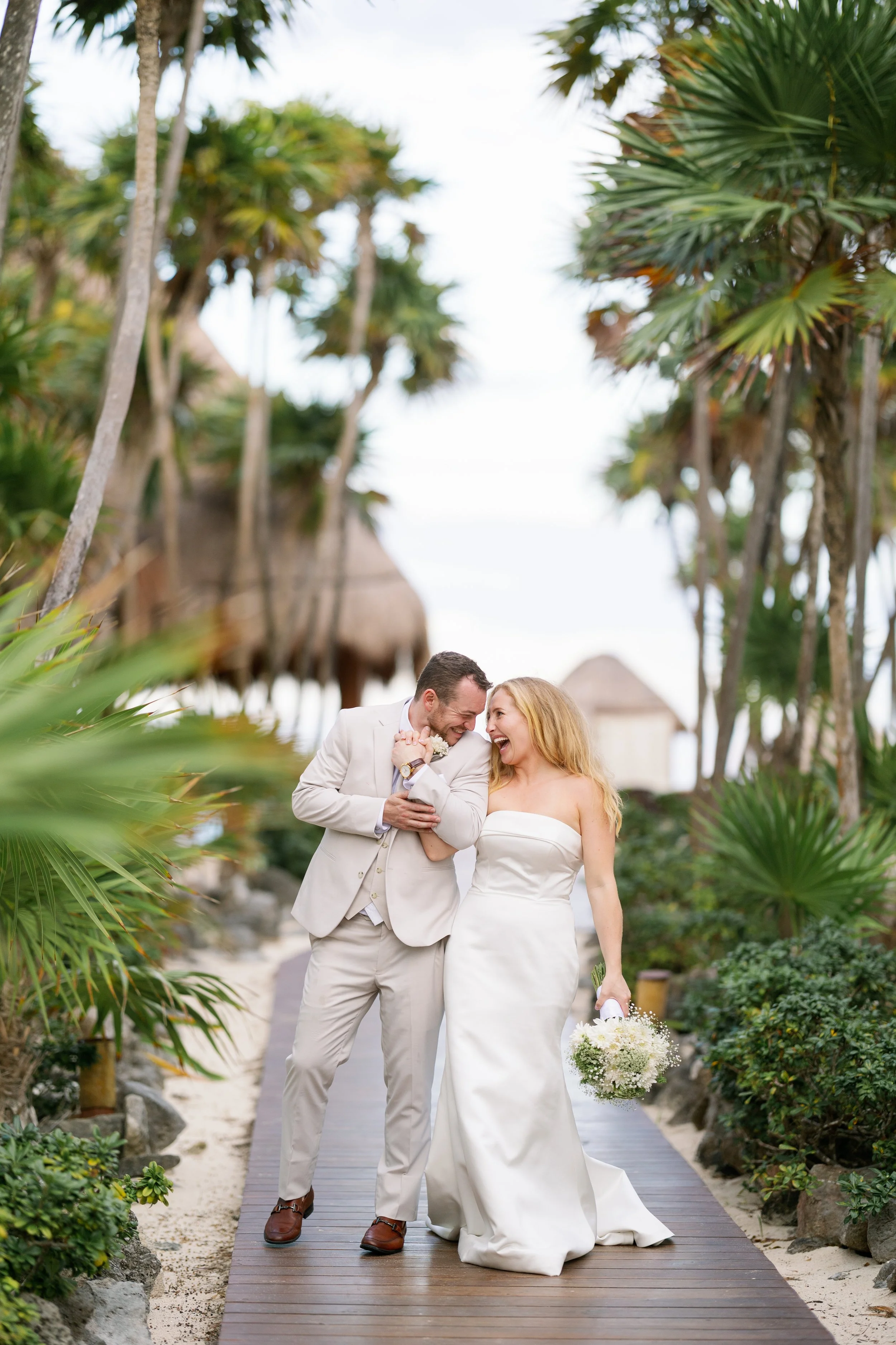 bride and groom walking down pathway smiling at each other at valentin imperial resort in riviera maya mexico