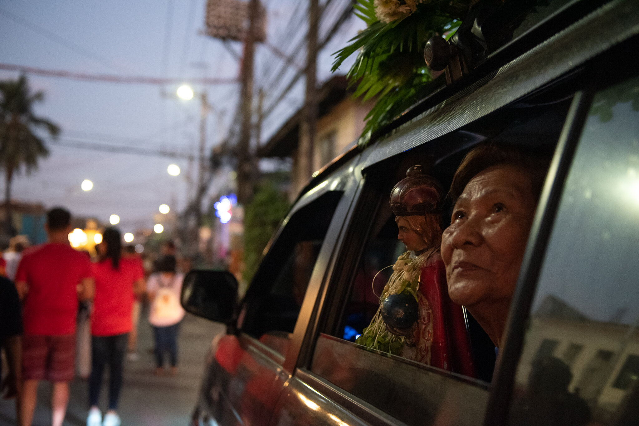  An old woman watches the procession from inside the car. 