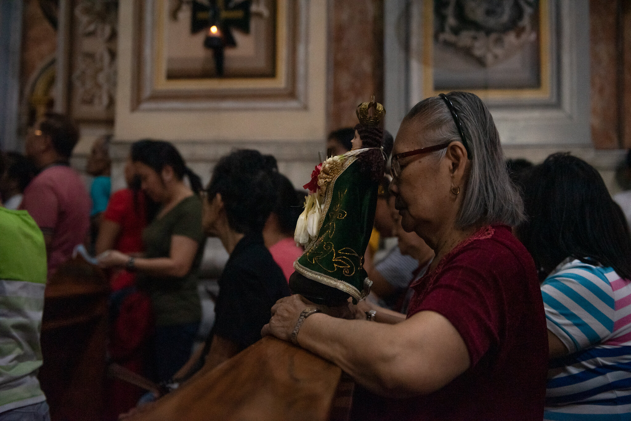  An old woman praying in church with an images of the Jesus. 