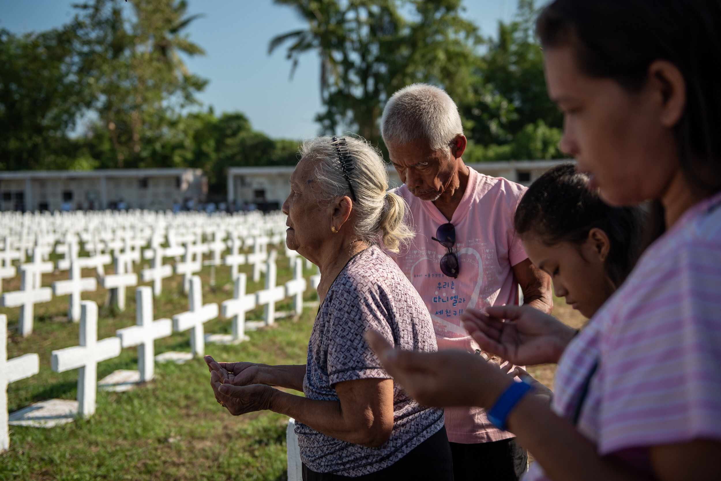  A family sings prayers for their deceased relative during the mass held at the Holy Cross Cemetery, Basper Village, Tacloban City, Leyte. 