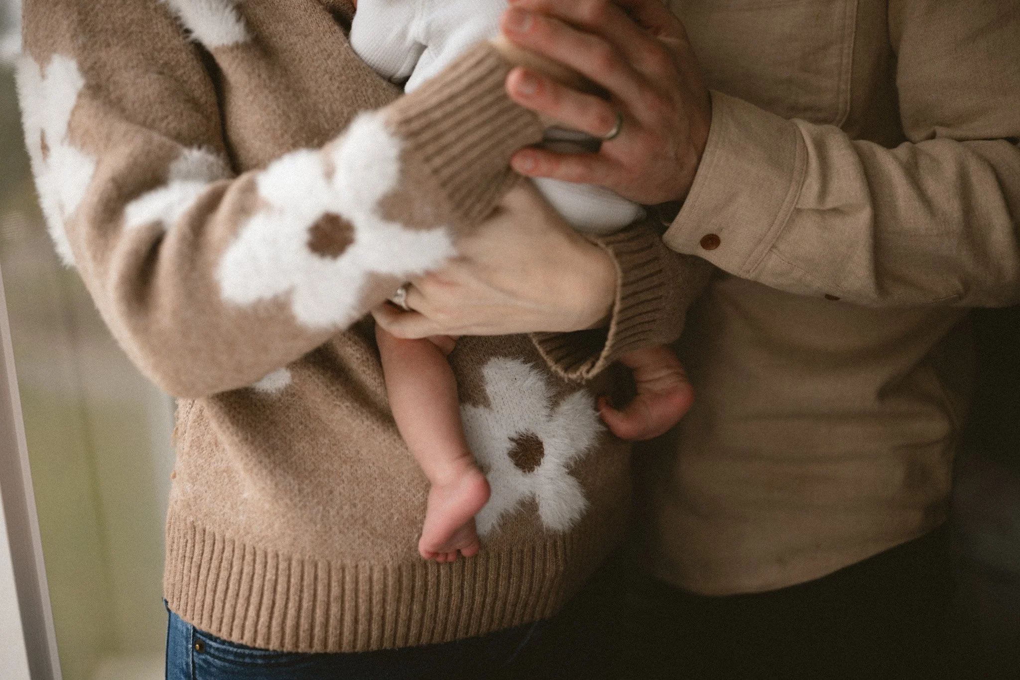 Close-up of a newborn’s tiny feet resting in their parents’ hands during a cozy in-home newborn photography session in Seattle.