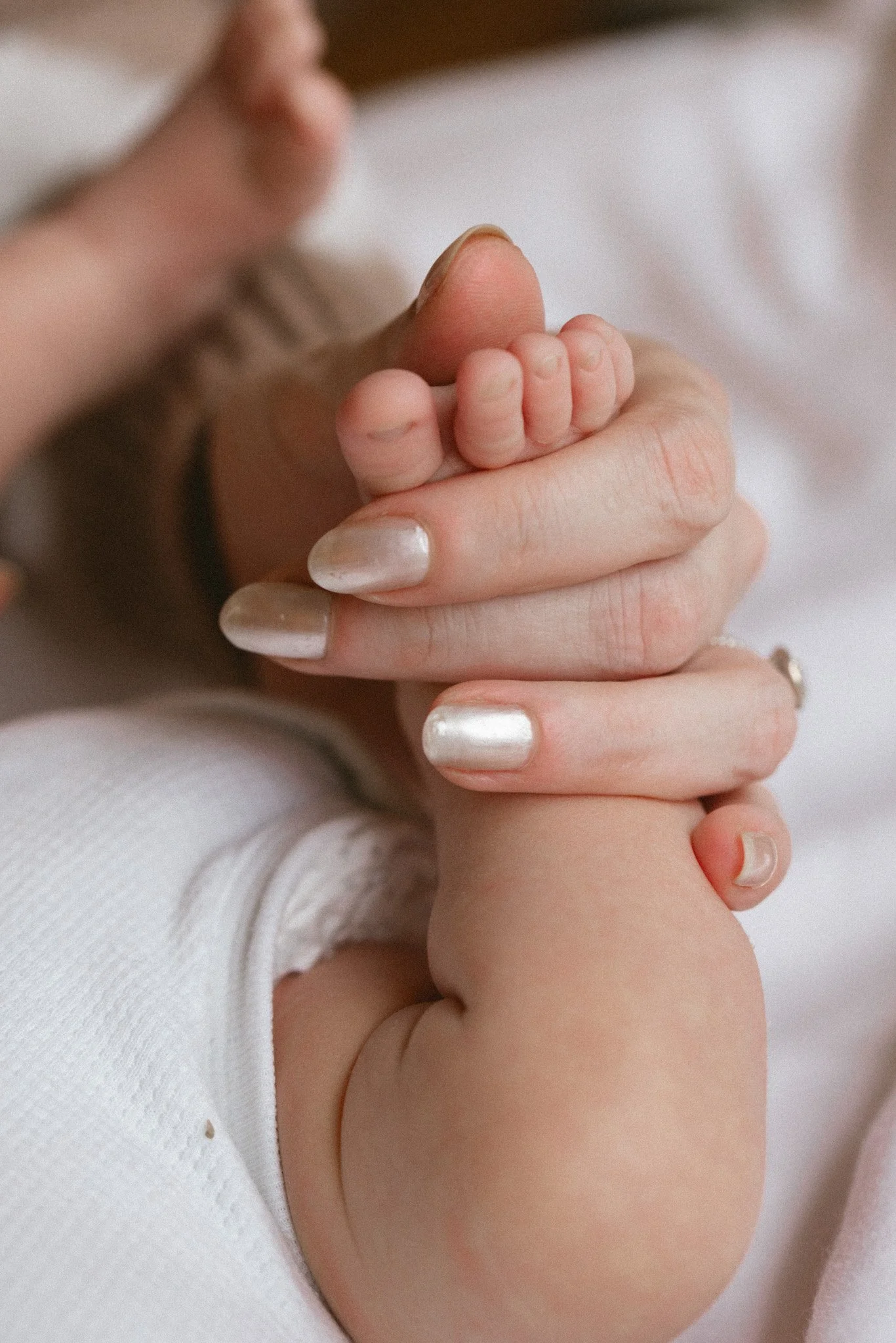 A mother gently holds her newborn baby’s tiny foot during a calm in-home newborn photography session in Seattle.