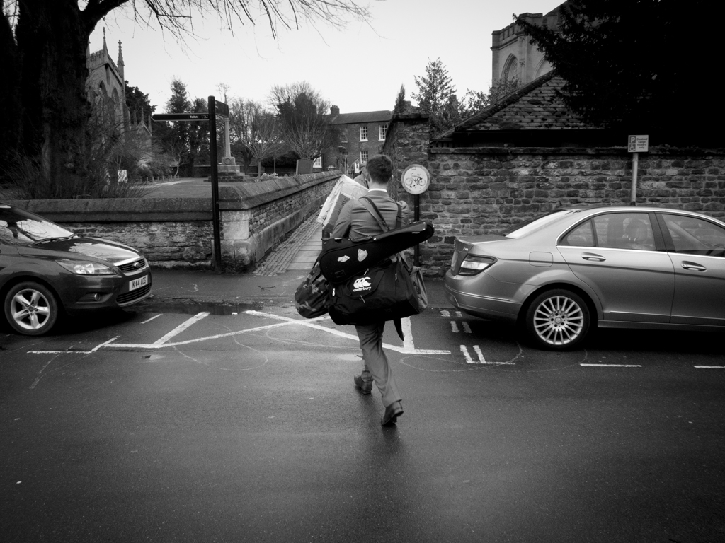 Thomas marching off to school with his sports bag, violin, over night bag, books bag and huge art A level sketchbook. Church Street. February 2013