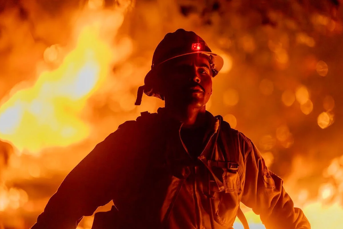 Firefighter with fire in background; © David McNew / Greenpeace