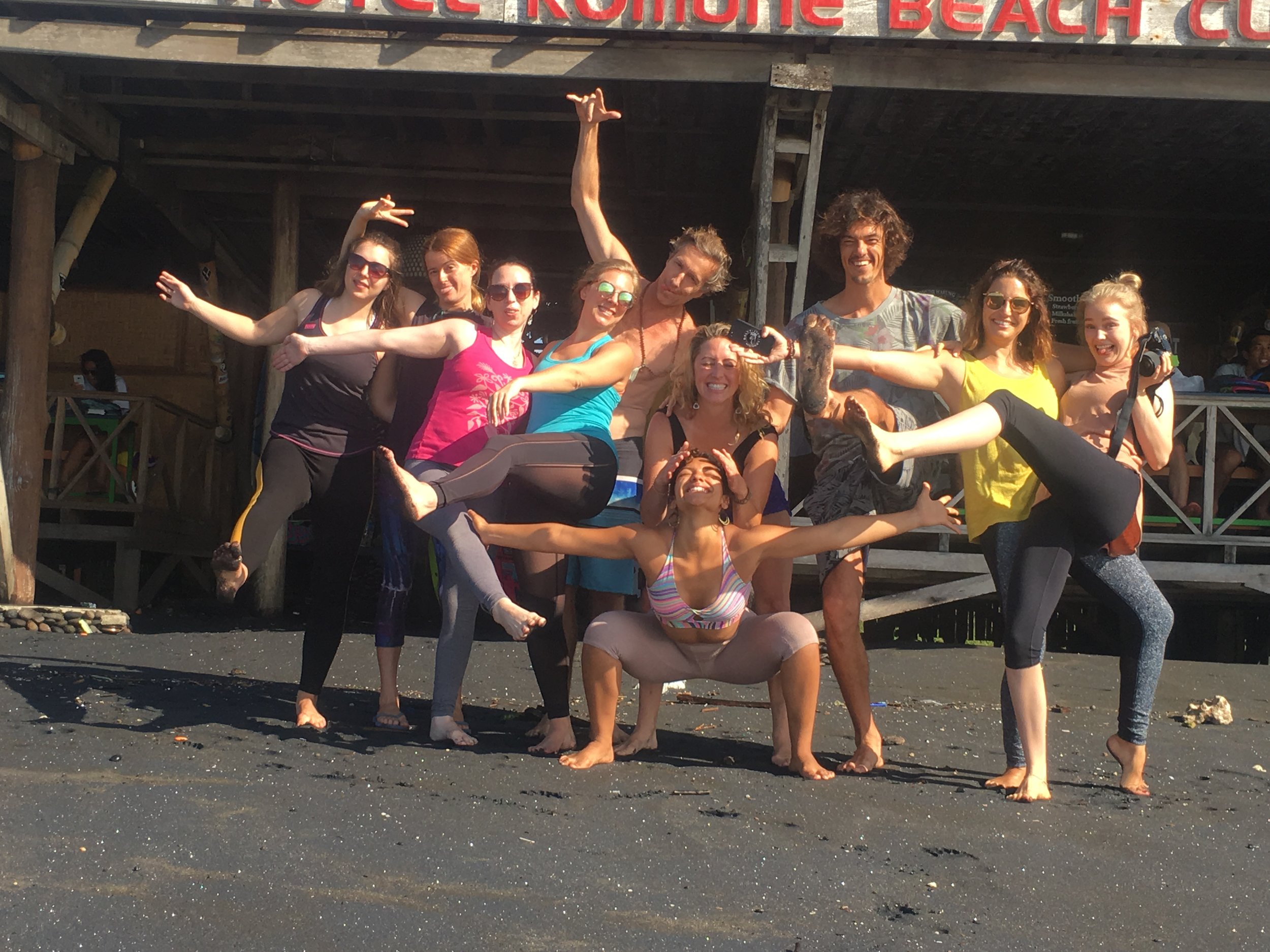 Yoga retreat group posing on black sandy Balinese beach  (Copy)