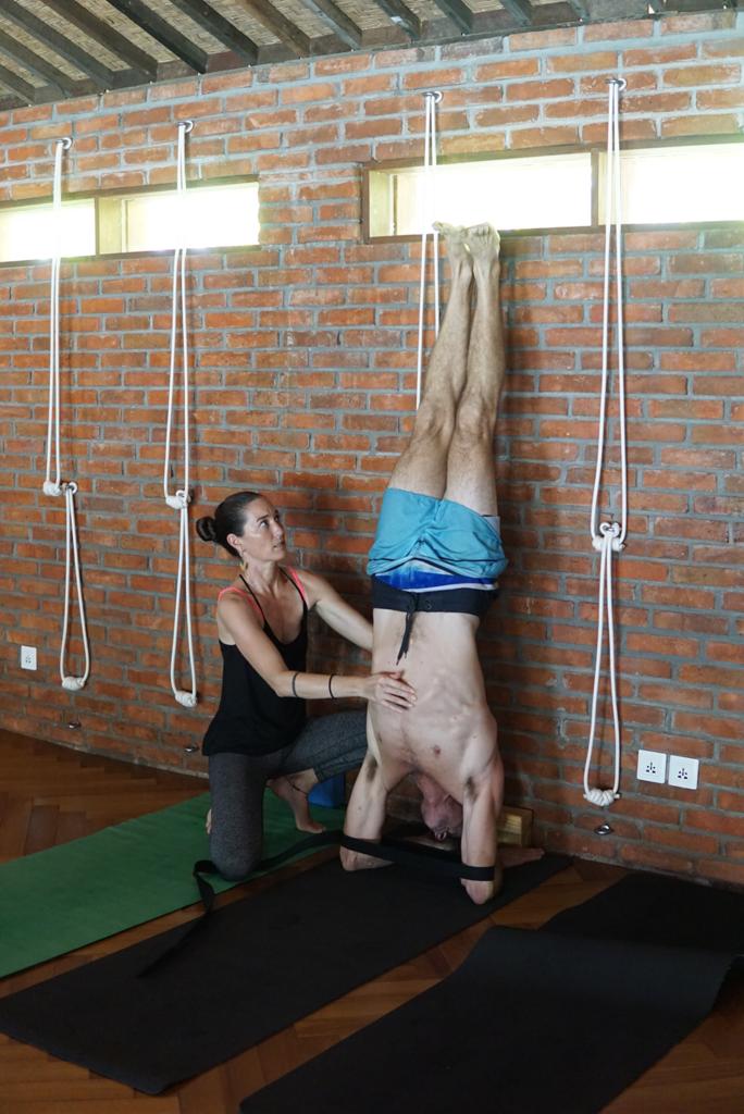 Vinyasa teacher trainer Nicole guiding student through supported feathered peacock pose (Copy)