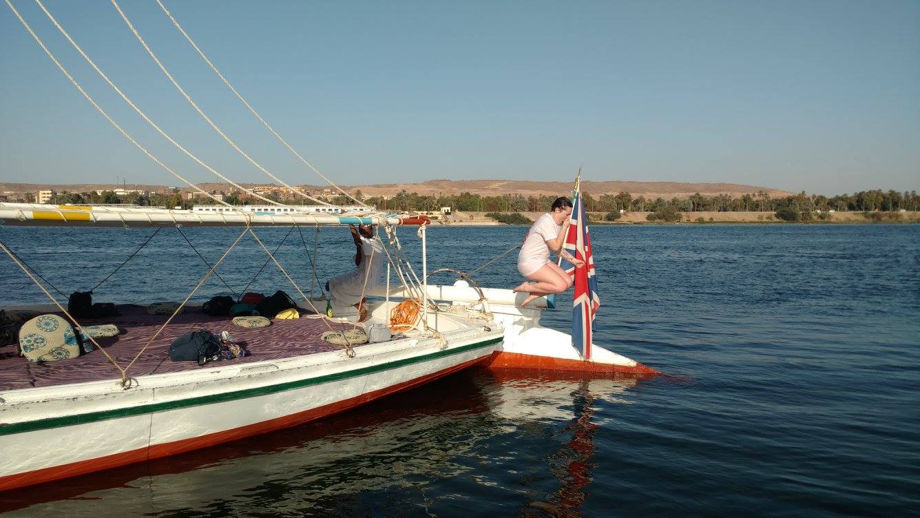 Egypt travel tips: Women wearing a white shirt holding her nose and jumping off a sail boat into the river NIle.