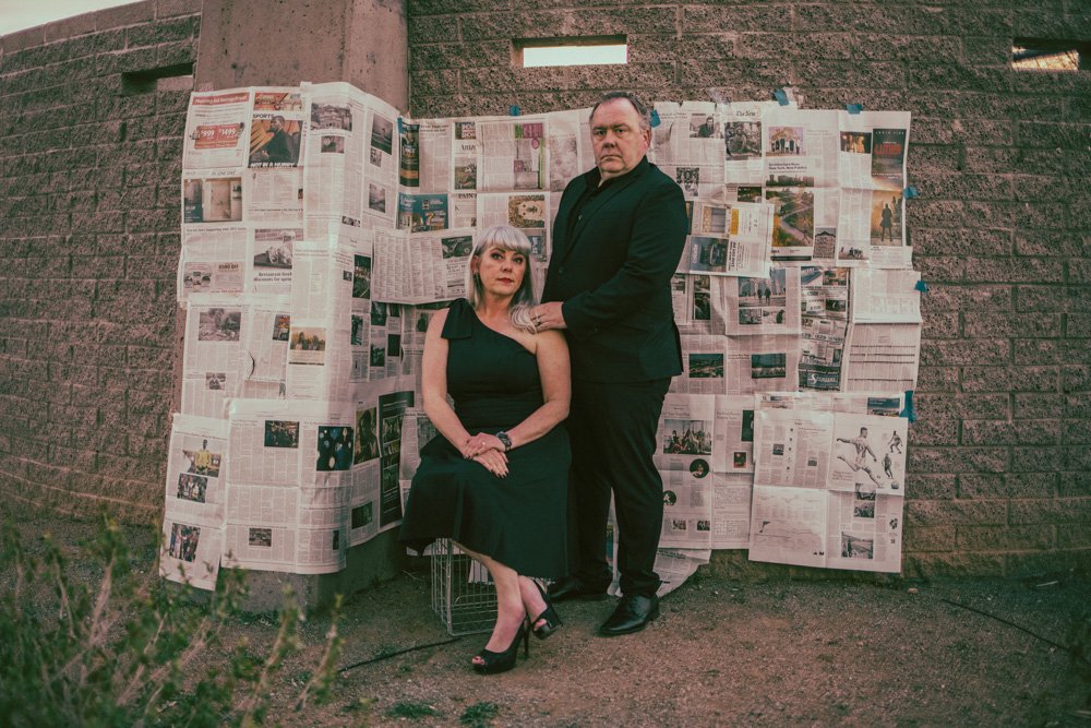 Family poses in front of handcrafter newspaper backdrop for creative session with creative phoenix photographer; Jennifer Lind Schutsky. 