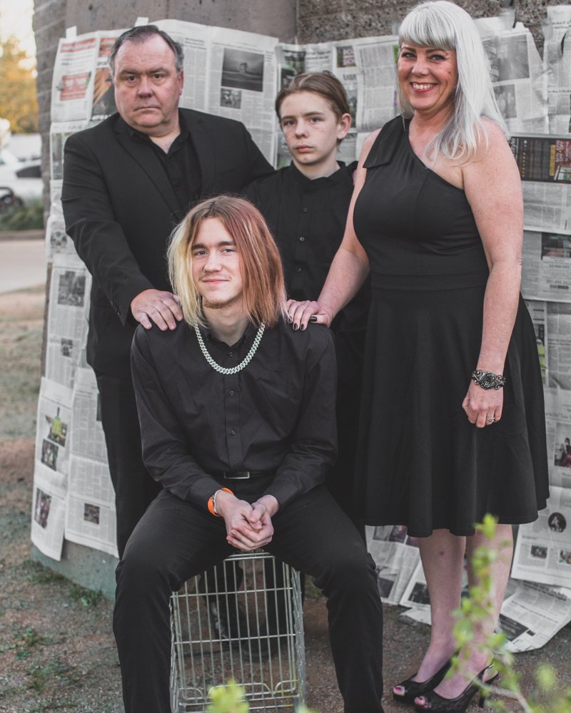 Family poses in front of handcrafter newspaper backdrop for creative session with creative phoenix photographer; Jennifer Lind Schutsky. 