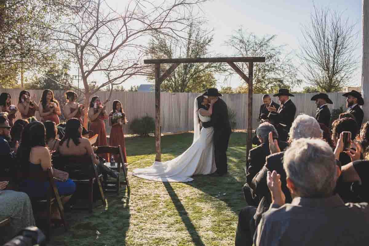  Bride and Groom share their first kiss at Mexican Cowboy / Vaquero Farm Wedding at the Big Red Barn wedding at Schnepf Farms in Queen Creek, Arizona by Arizona based Photographer, Jennifer Lind Schutsky. 
