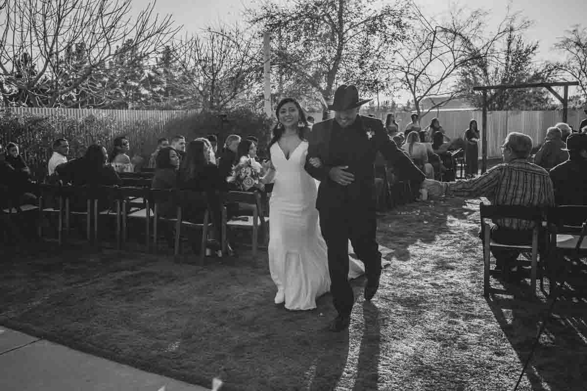  Bride and Groom walk down the aisle as newlyweds at Mexican Cowboy / Vaquero Farm Wedding at the Big Red Barn wedding at Schnepf Farms in Queen Creek, Arizona by Arizona based Photographer, Jennifer Lind Schutsky. 