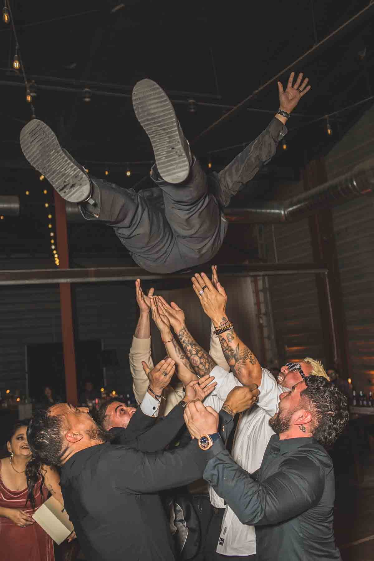  Groomsmen toss groom in the air at  Wedding Reception Celebration at Mexican Cowboy / Vaquero Farm Wedding at the Big Red Barn wedding at Schnepf Farms in Queen Creek, Arizona by Destination Wedding Photographer, Jennifer Lind Schutsky. 