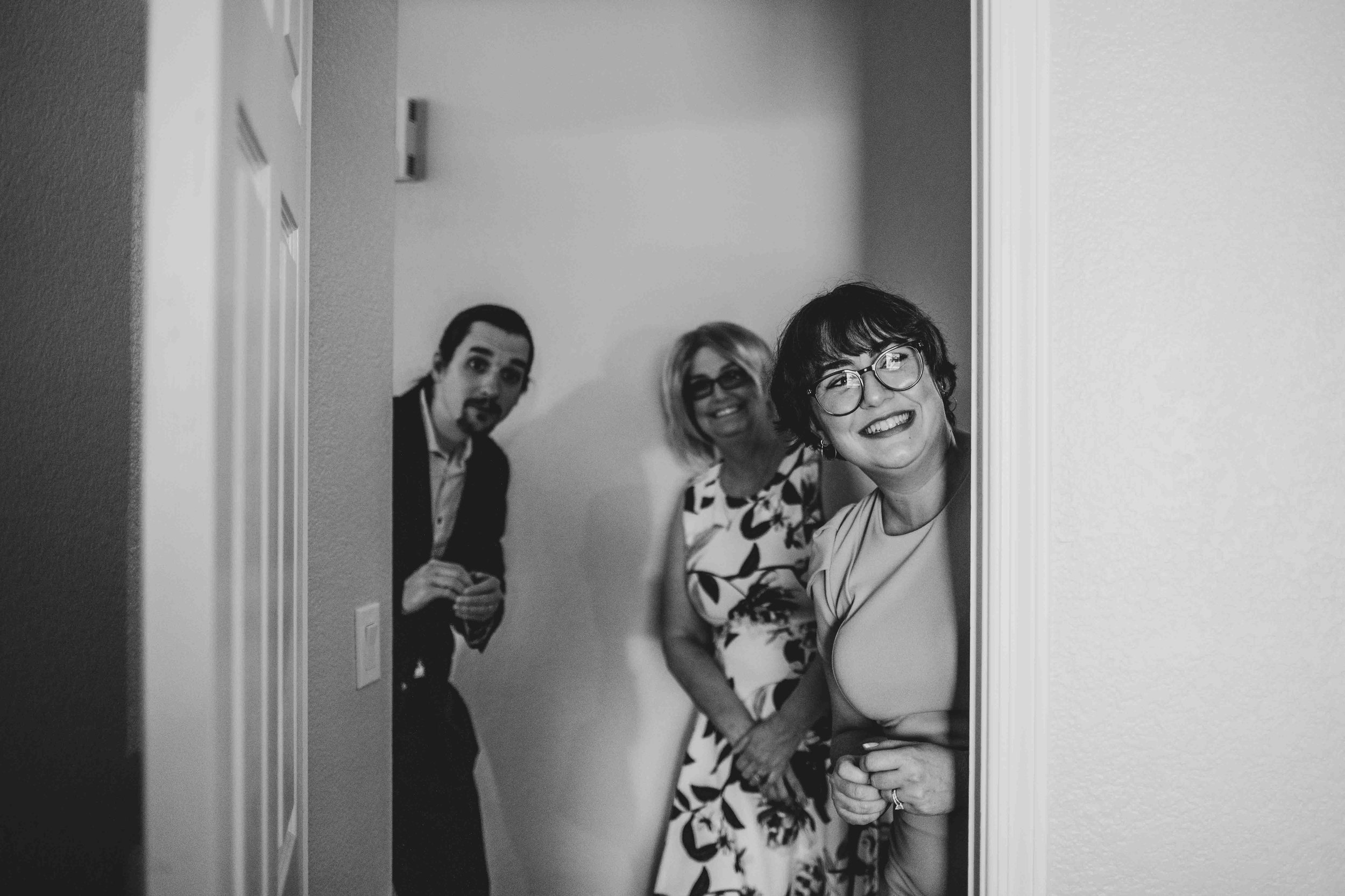  Family and friends watch Bride and Groom getting ready together for their wedding day at home by Gilbert Wedding Photographer Jennifer Lind Schutsky. 
