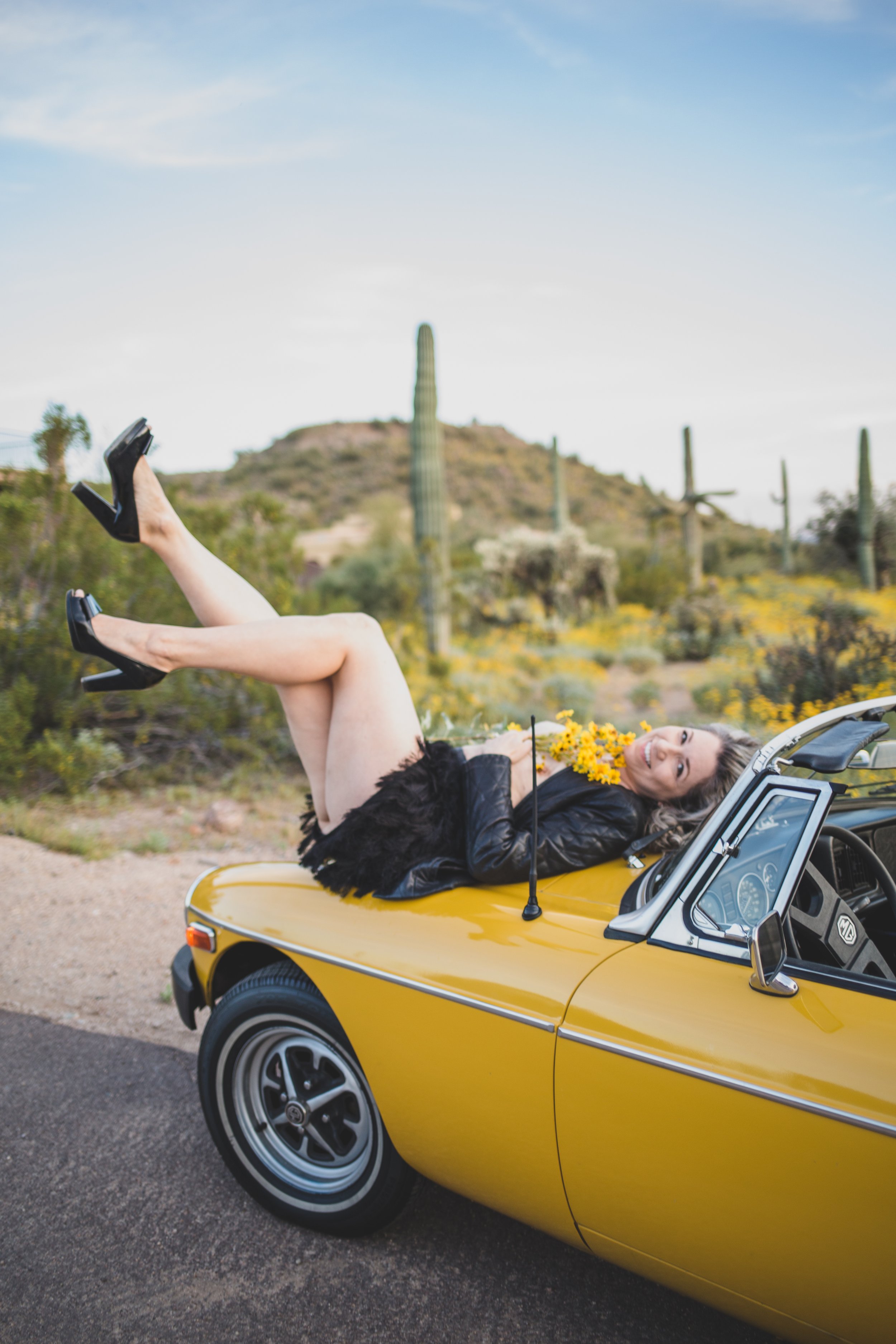 Breast Cancer Survivor poses for breast cancer survivor photoshoot with yellow MG sports car in Arizona desert with Phoenix Creative Photographer; Jennifer Lind Schutsky.