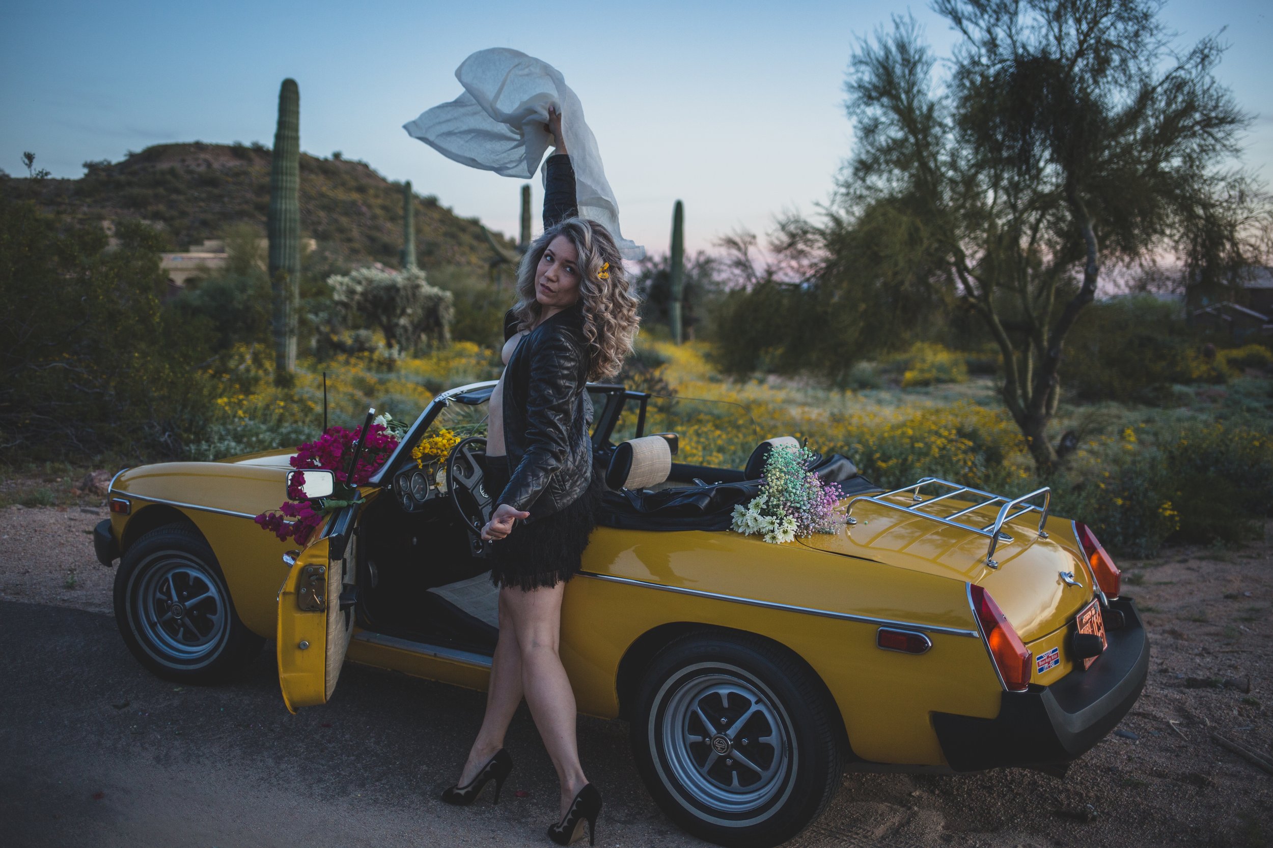 Breast Cancer Survivor poses for breast cancer survivor photoshoot with yellow MG sports car in Arizona desert with Phoenix Creative Photographer; Jennifer Lind Schutsky.