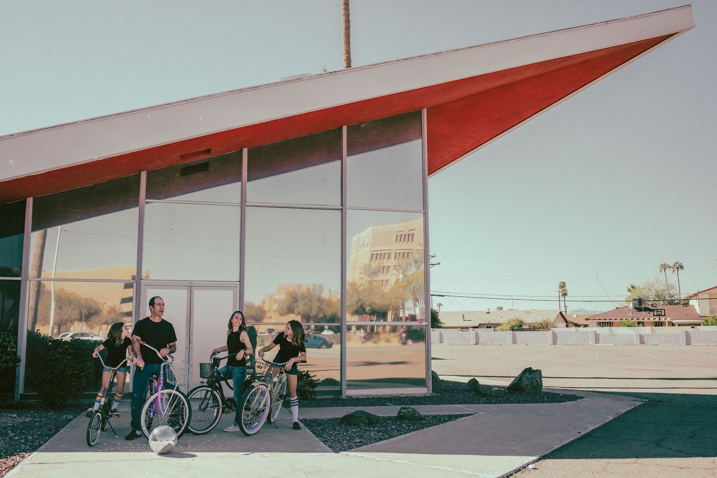 Family poses for their retro bike and skateboard photoshoot at Bowlero in Phoenix, Arizona by the most creative family photographer in Phoenix; Jennifer Lind Schutsky.